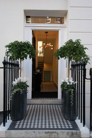 A black and white checkered entrance with two potted plants on either side. - B+B Belgravia (London)
