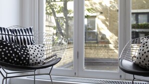 Una habitación con un ventanal grande, una silla con un cojín de lunares y un radiador.