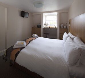 A hotel room with a large bed, a desk with a computer, a television, and a window with a view of the outdoors. - B+B Belgravia (London)