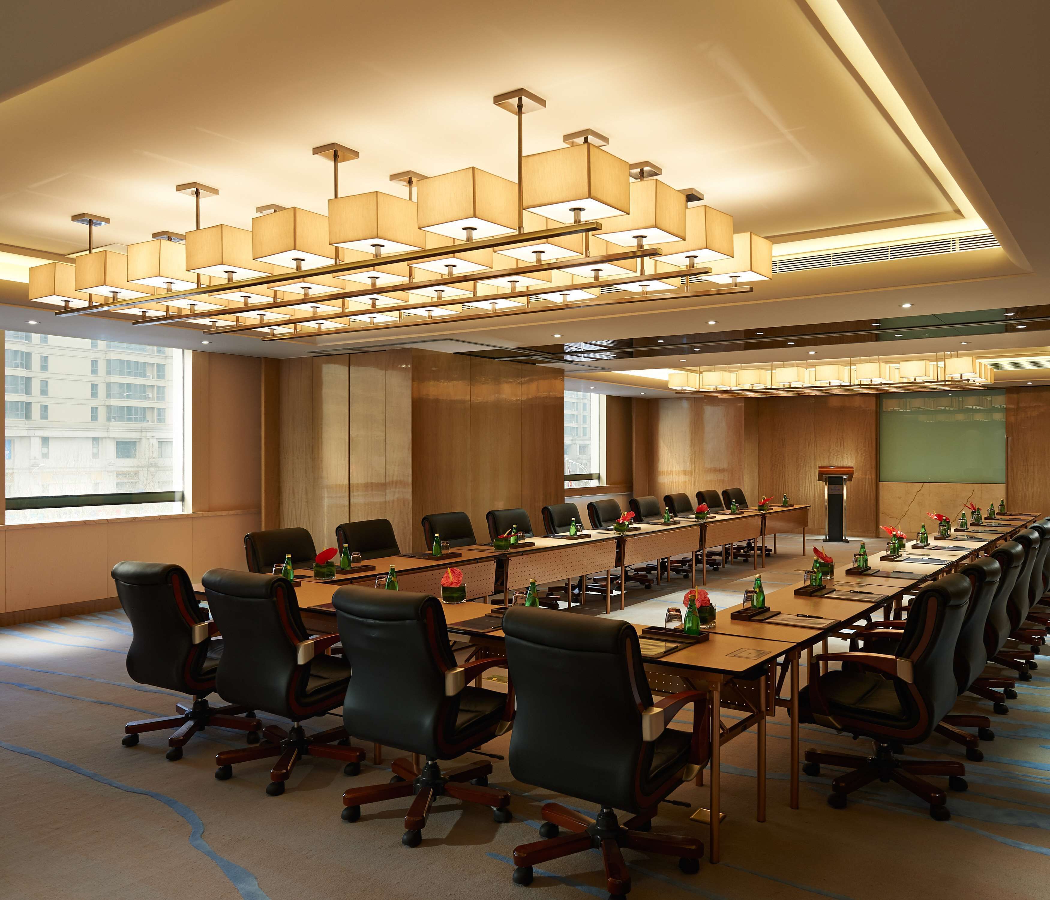A conference room with a long table, multiple chairs, and a projector screen.
