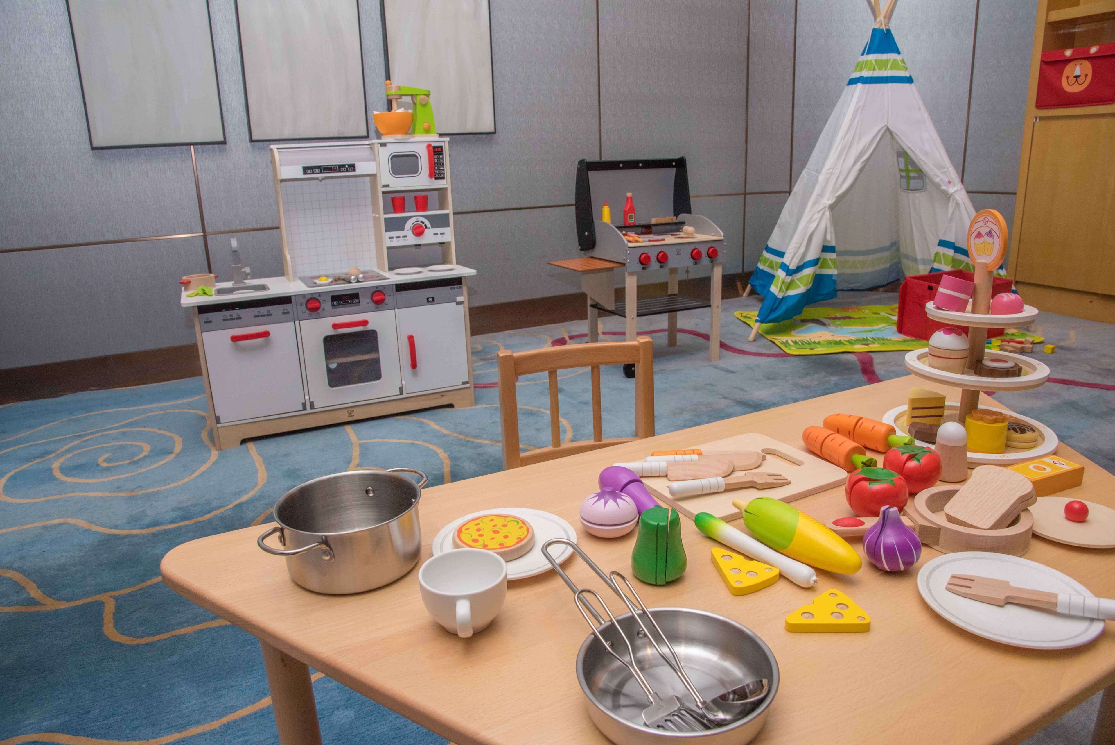 Un juego de cocina instalado en una habitación con alfombra azul, una tienda blanca y un televisor.