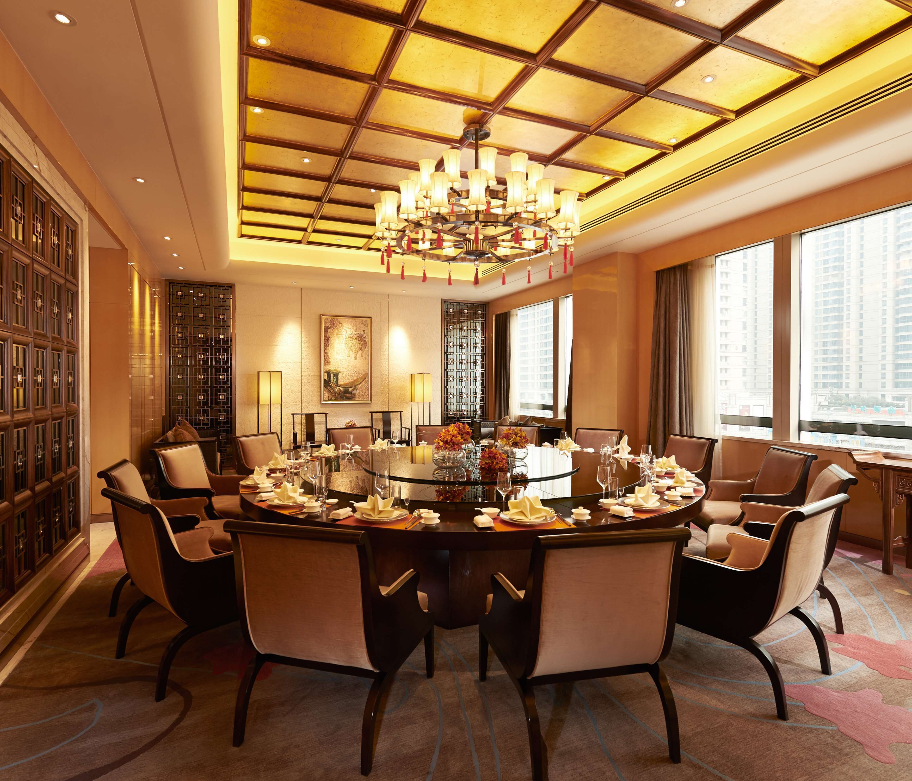 A conference room with a round table, chairs, and a chandelier.