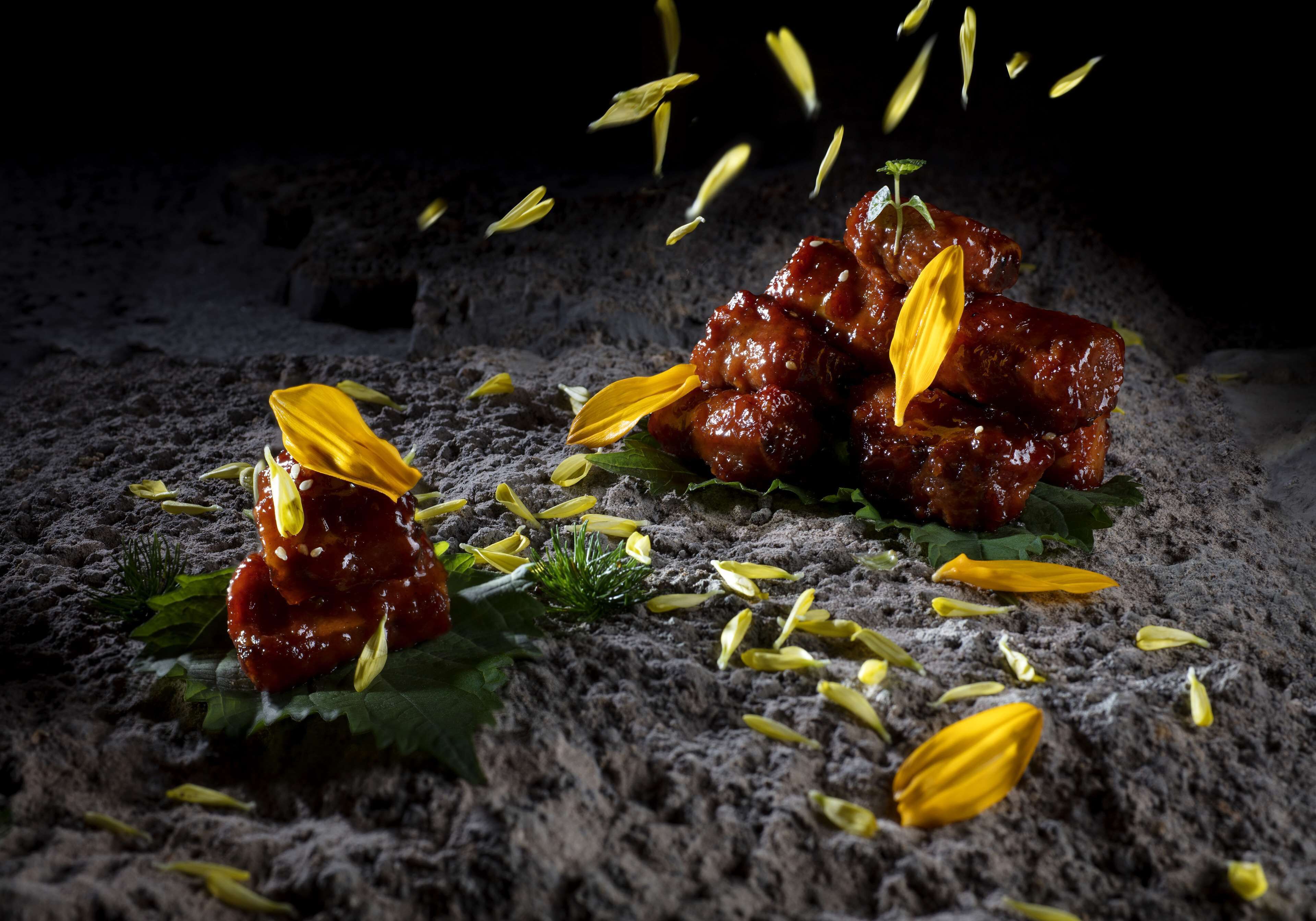 Un plat contenant de la viande et des feuilles jaunes, posé sur une surface texturée.