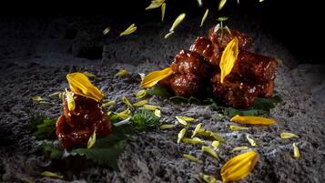 Un plat contenant de la viande et des feuilles jaunes, posé sur une surface texturée.