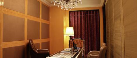 Une chambre d’hôtel équipée d’un bureau, de deux chaises, d’une lampe et d’un lustre.