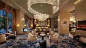 A spacious lobby with a large chandelier, comfortable seating, and a bar area. - Hilton Zhengzhou (Zhengzhou)