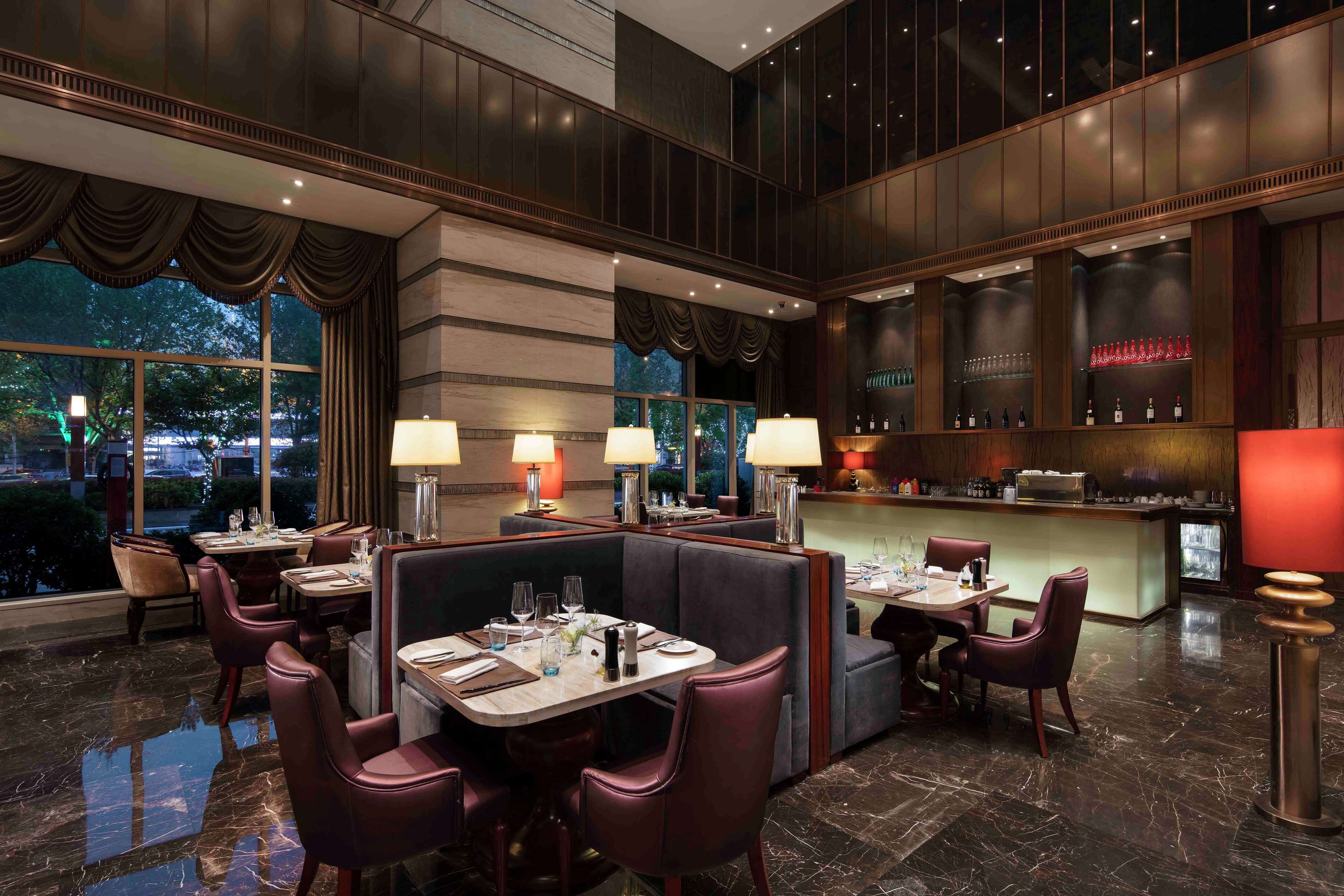 A high-end restaurant with marble flooring, leather booths, and a bar area with a red-lit counter.