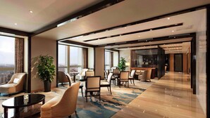 A spacious hotel lobby with modern furniture, large windows, and a view of the city. - Hilton Zhengzhou (Zhengzhou)