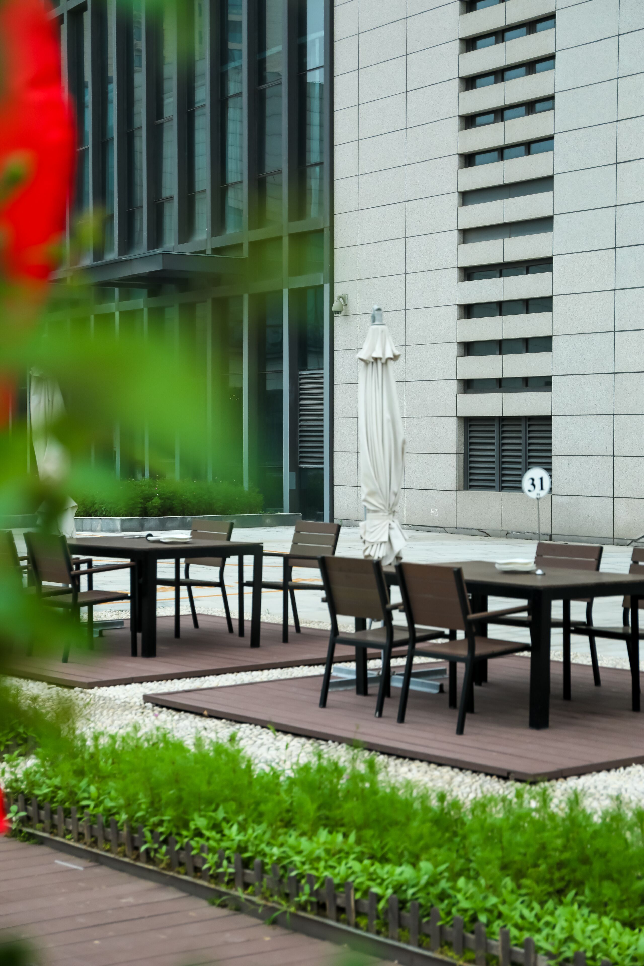 An outdoor seating area with tables and chairs, a building in the background, and a speed limit sign.