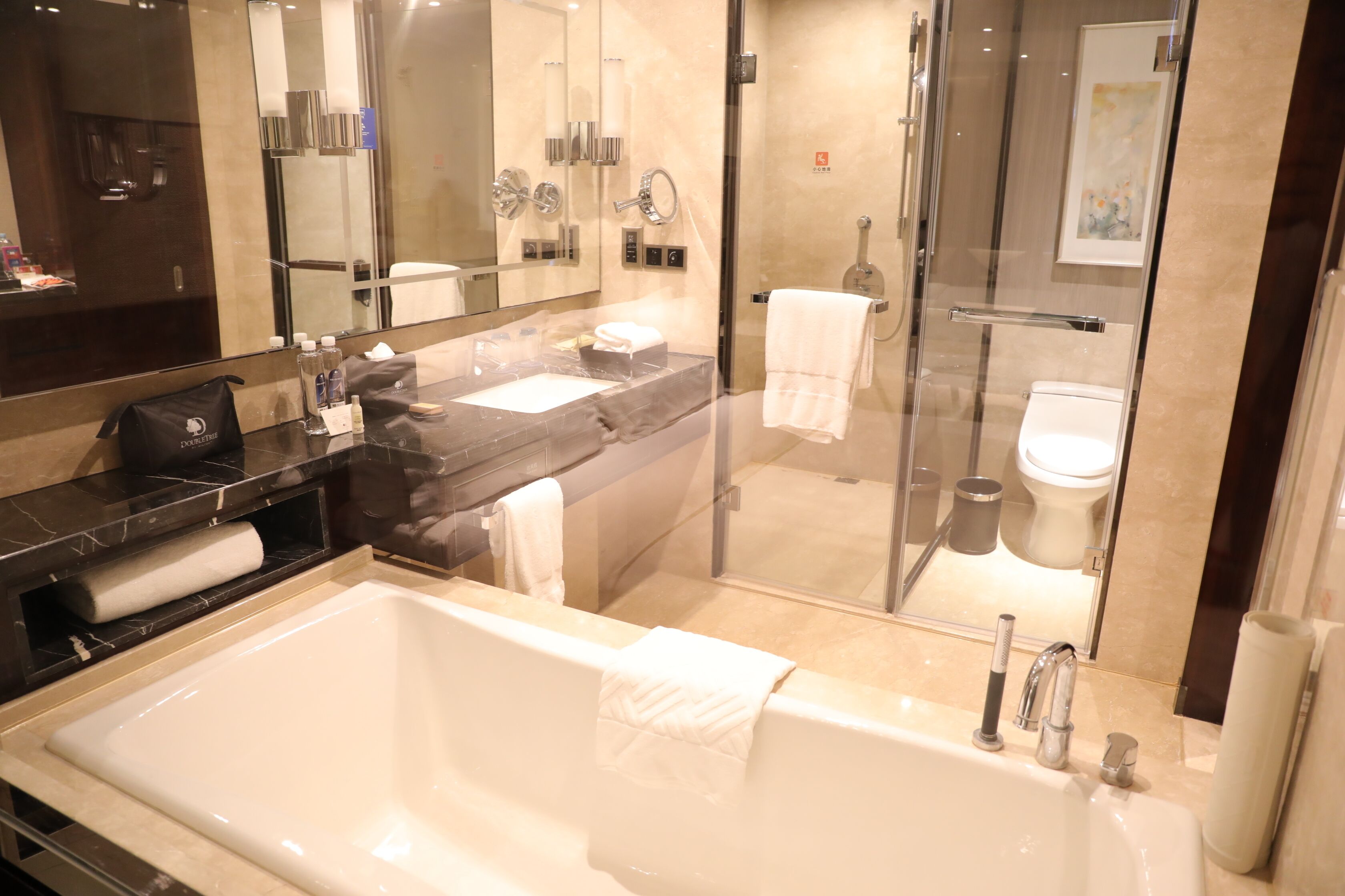 A modern bathroom with a large bathtub, a separate shower area, and a glass-enclosed toilet.