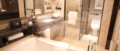 A modern bathroom with a large bathtub, a separate shower area, and a glass-enclosed toilet.