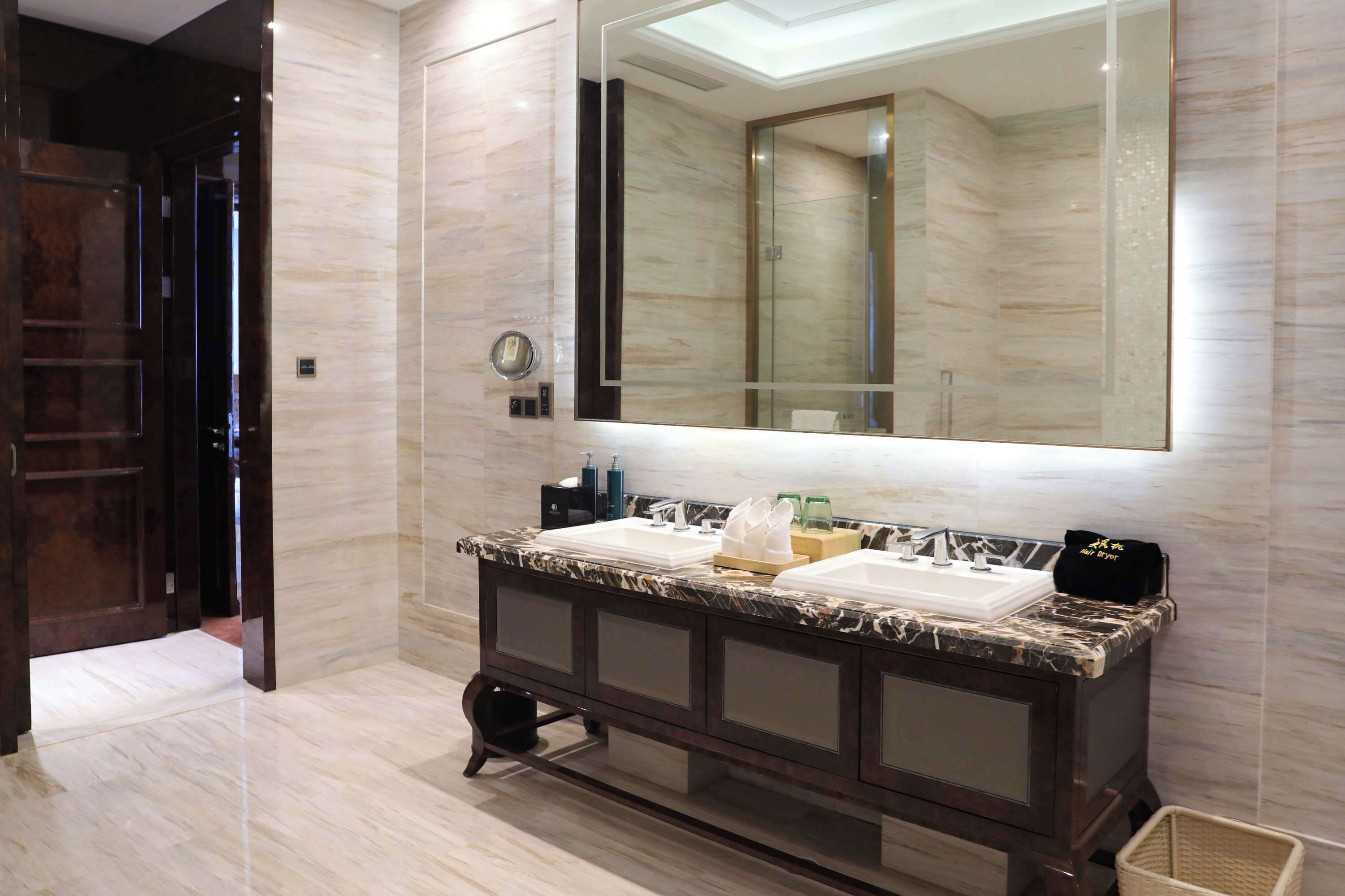 A modern bathroom with a marble vanity, a large mirror, and a walk-in shower.
