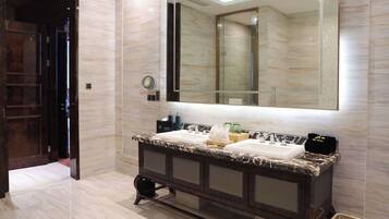 A modern bathroom with a marble vanity, a large mirror, and a walk-in shower.
