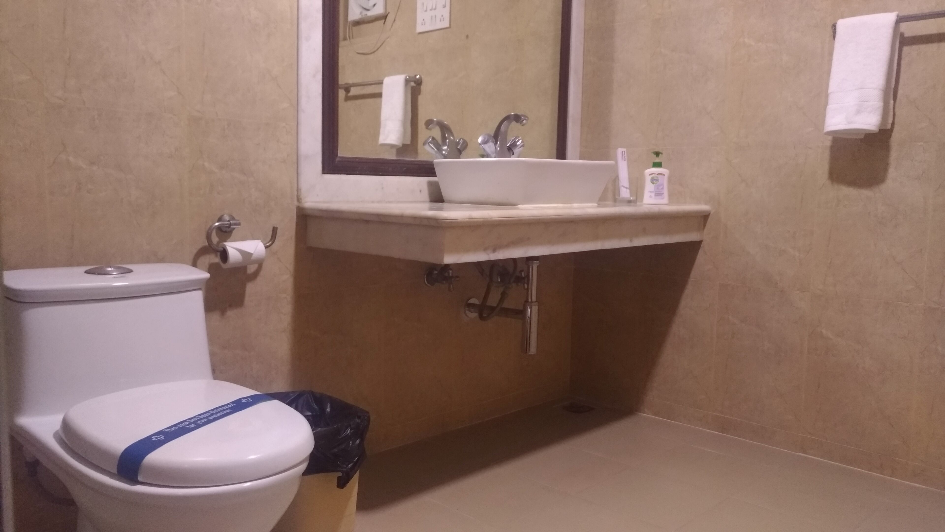 Een badkamer met toilet, wastafel en spiegel.
