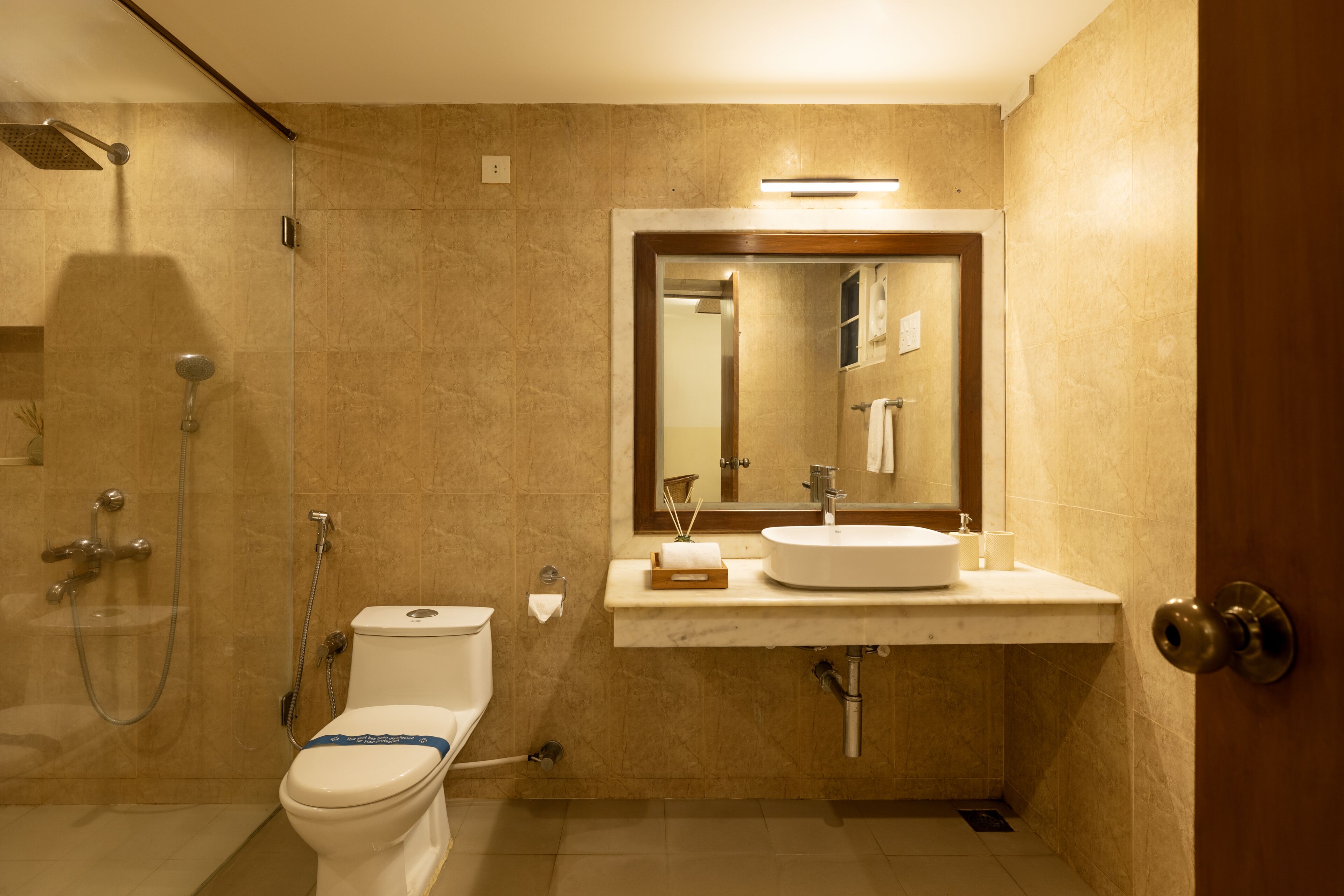 A bathroom with a toilet, sink, mirror, and shower.