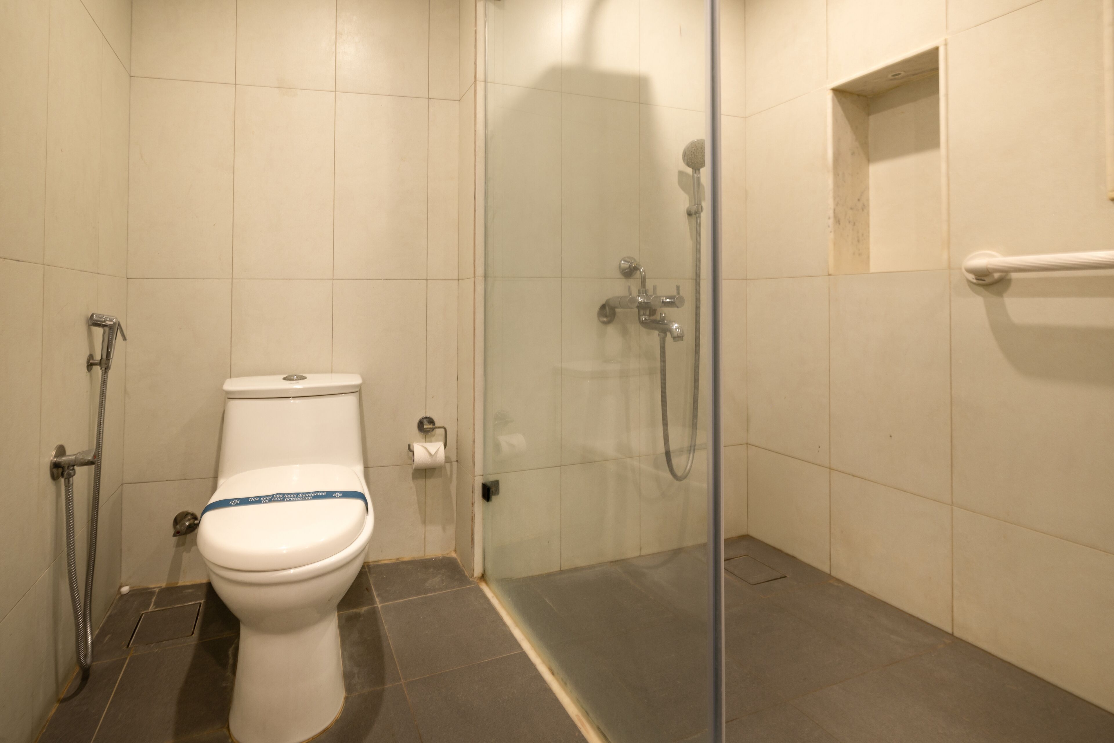 Een badkamer met toilet, douche en glazen deur.