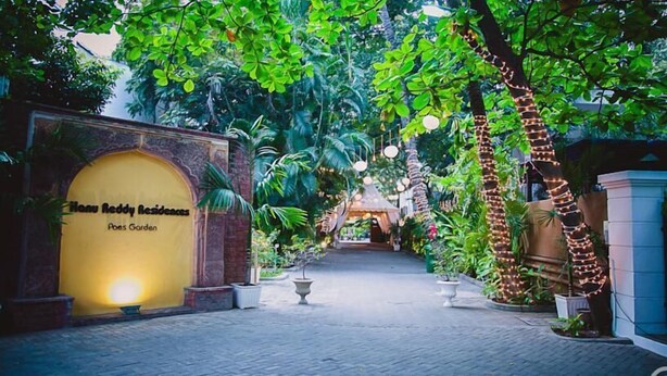 Ein Weg führt zu einem Gebäude, an dem ein Schild mit der Aufschrift 'Menu Reddy Residences' zu sehen ist.