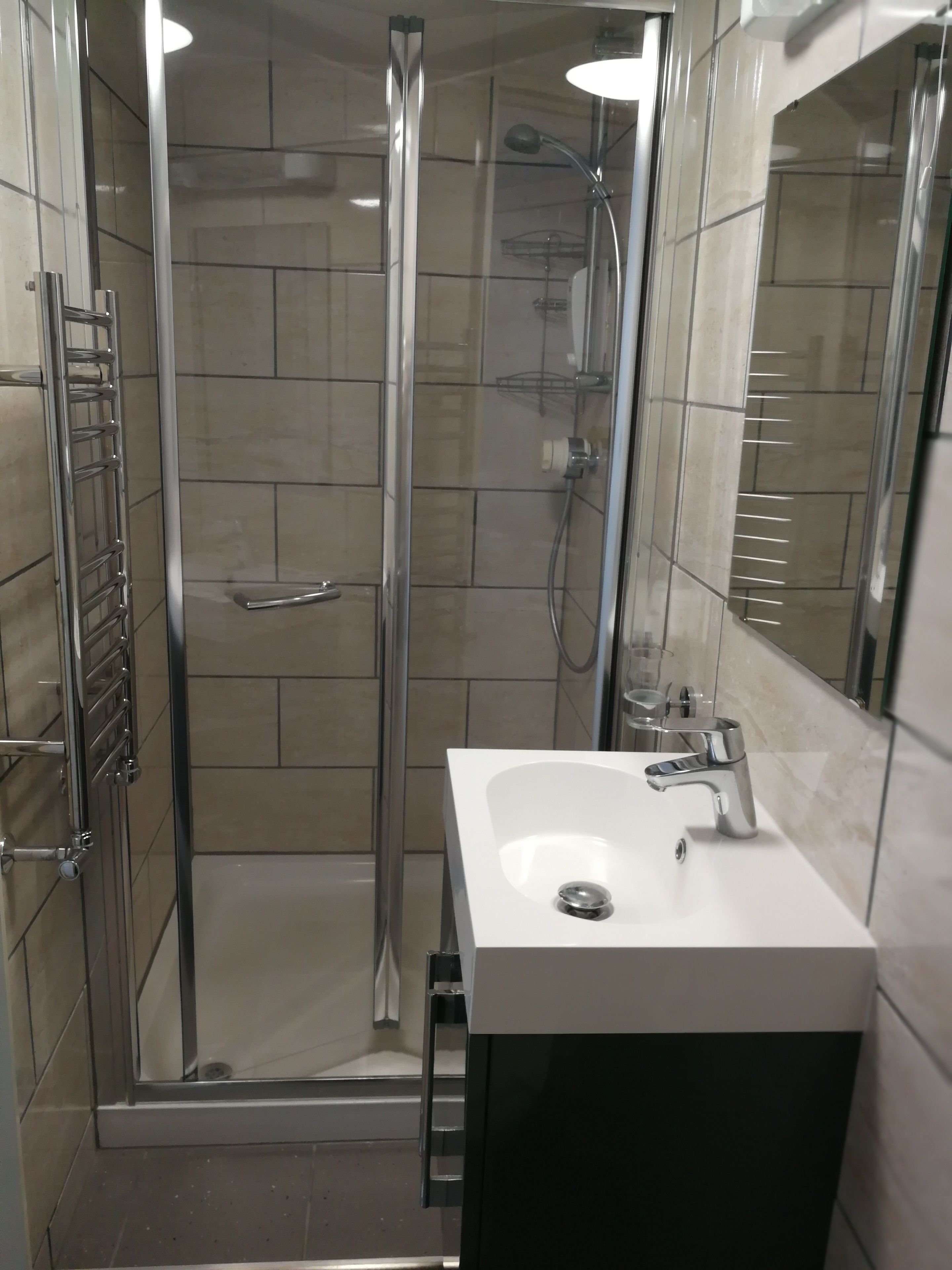 A modern bathroom with a glass-enclosed shower, a white sink, and a mirror.