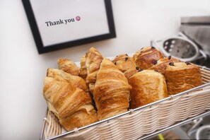 A basket of croissants on a table with a 'Thank you' sign in the background. - NOX HOTELS - Belsize Park (London)