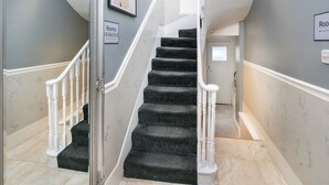 A staircase with black carpeted steps and white balusters, leading to a door labeled "Rooms 3,5-8 & 10-12". - Apollo Hotel Kings Cross (London)