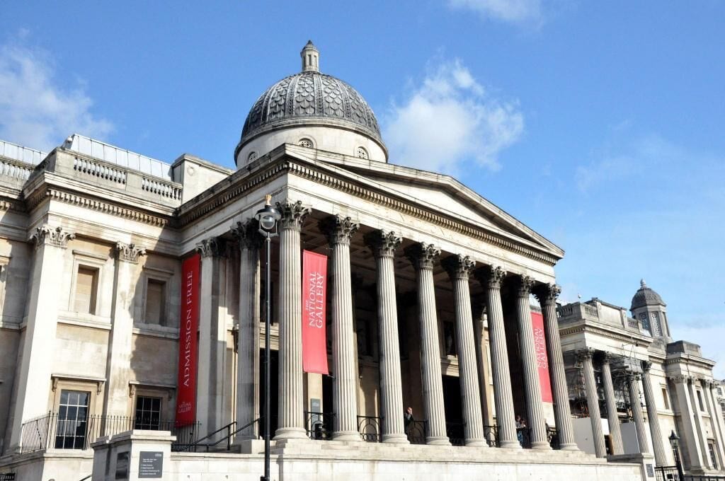 A classical building with a prominent dome and columns, featuring banners that read "Admission Free."