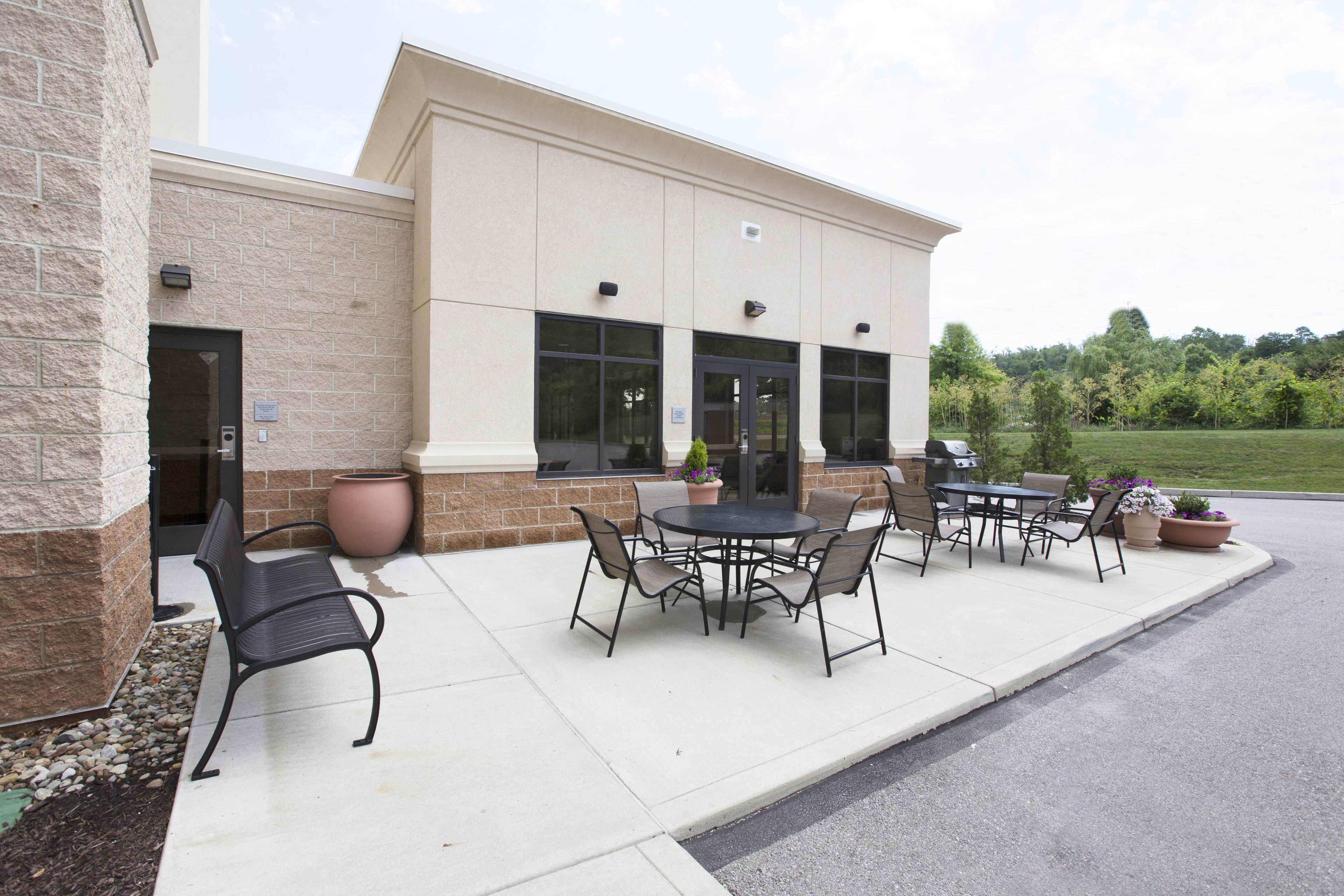 An outdoor patio area with a table and chairs, a potted plant, and a building entrance.