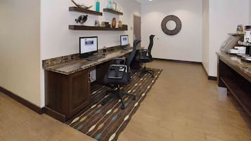 Un área de recepción con mostrador de mármol, dos monitores de computadora, una silla de oficina negra y estanterías decorativas.