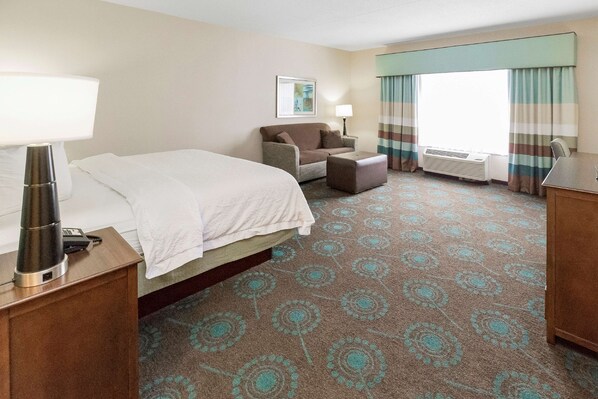 A hotel room with a bed, a sofa, a desk, a lamp, a picture on the wall, and a window with curtains. - Hampton Inn Pittsburgh-Bridgeville (Bridgeville)