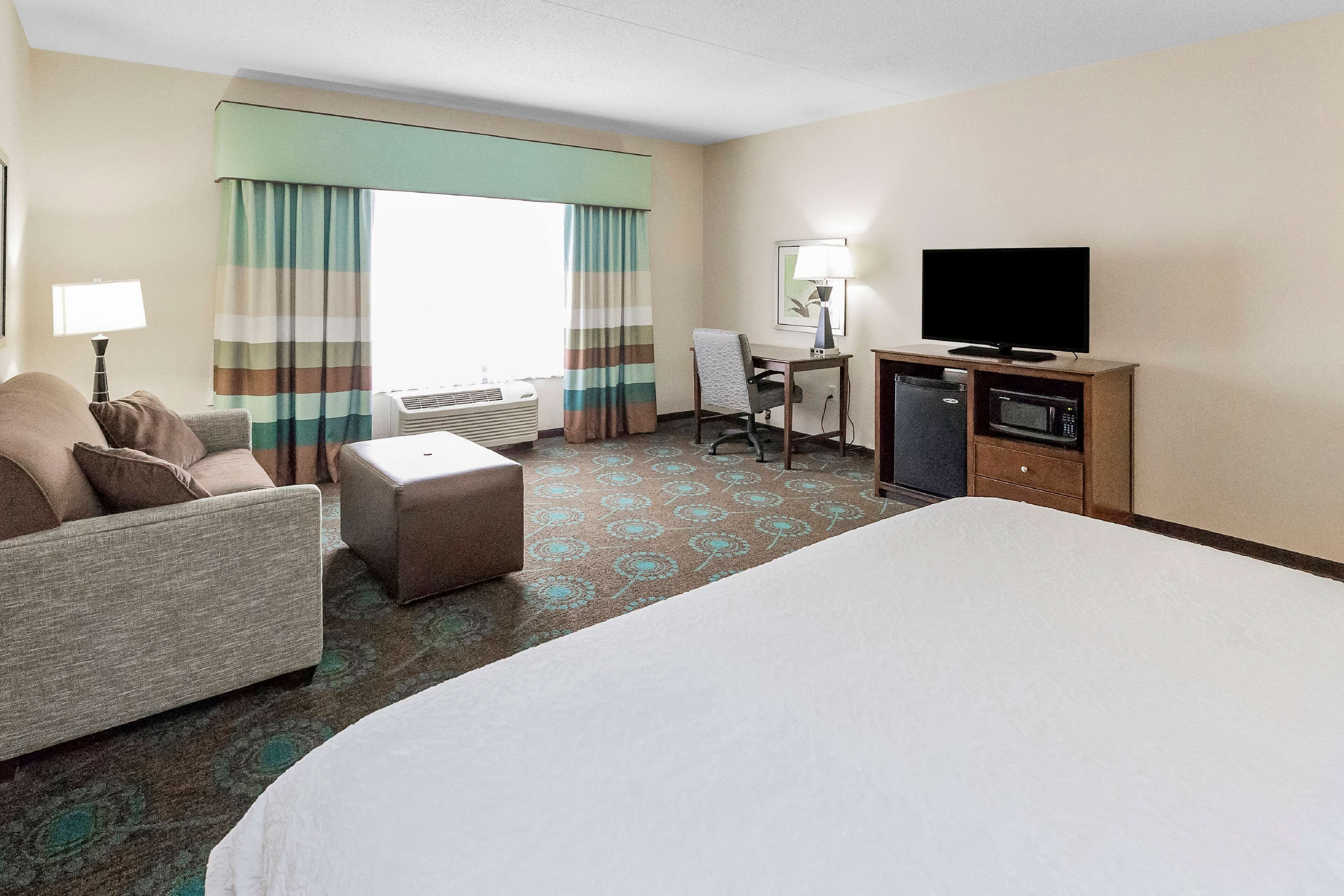 A hotel room with a bed, a desk, a television, and a microwave.