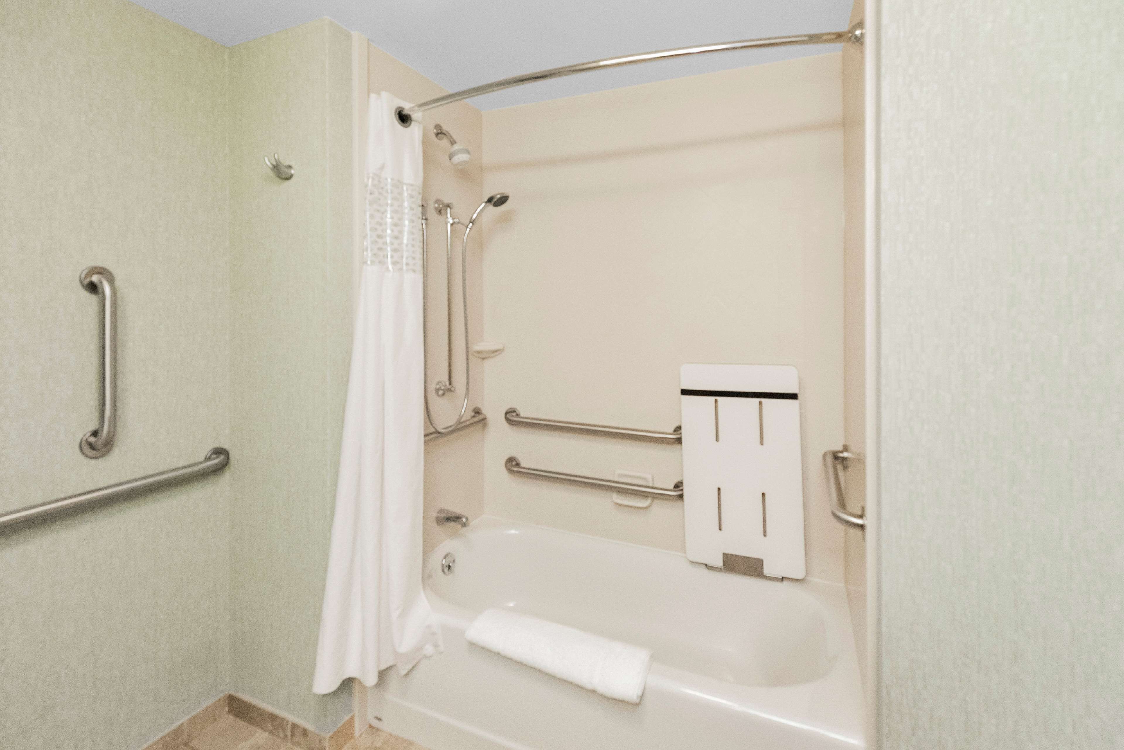 Ein Badezimmer mit einer Badewanne, Haltegriffen, einer Duschvorhang und einem Handtuchhalter.