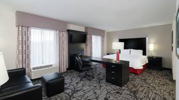 A hotel room with a bed, desk, chair, and TV.
