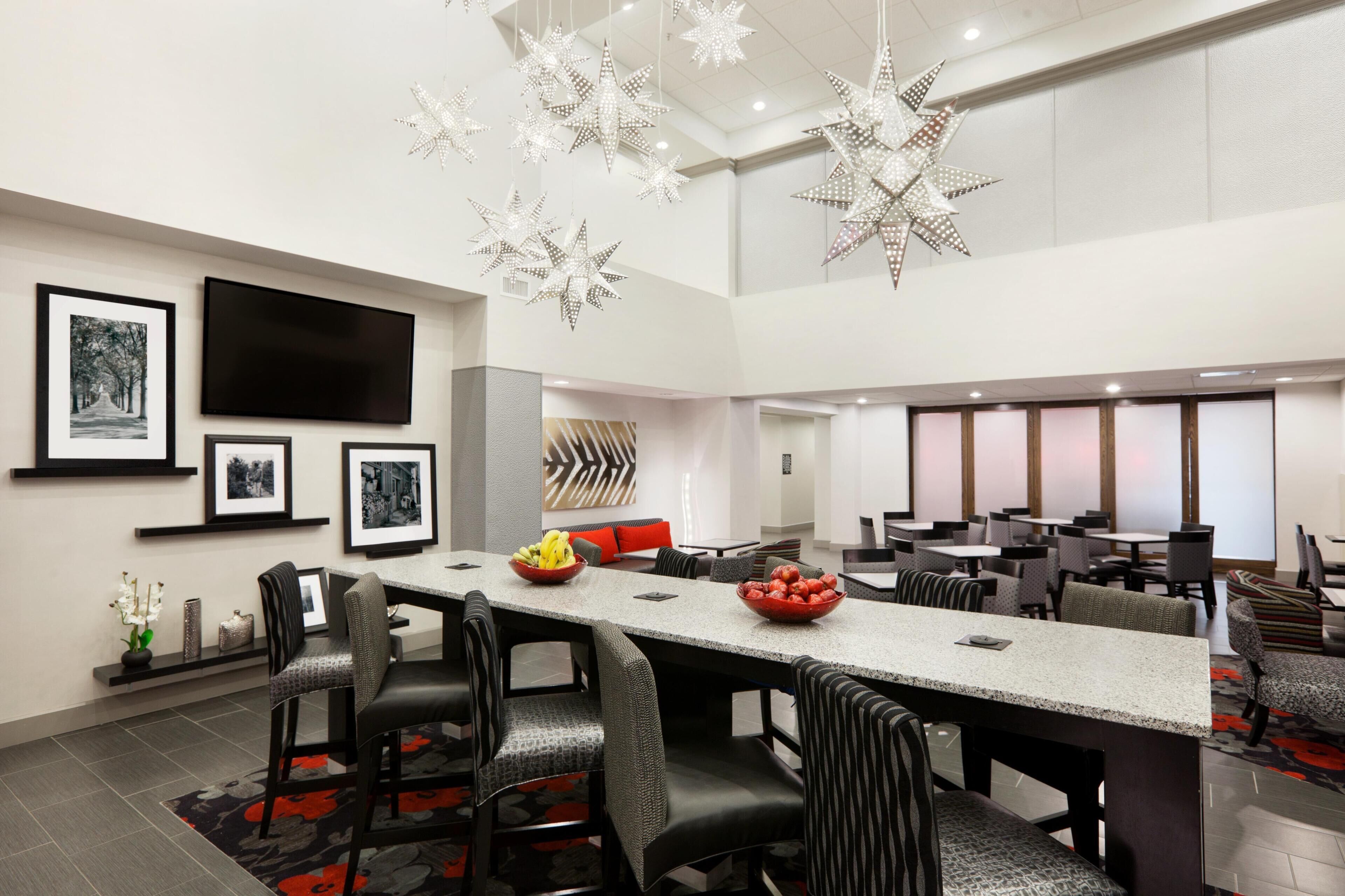 A modern dining area with a long table, chairs, and decorative star lights.