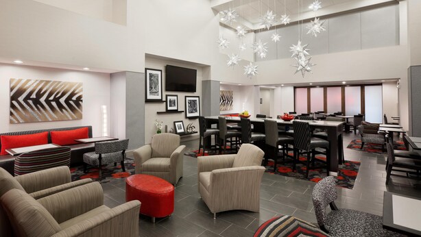 A spacious hotel lobby with modern furniture, a dining area, and a large chandelier. - Hampton Inn & Suites Roanoke Airport (Roanoke)