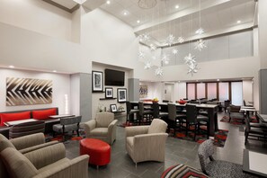 A spacious hotel lobby with modern furniture, a dining area, and a large chandelier. - Hampton Inn & Suites Roanoke Airport (Roanoke)