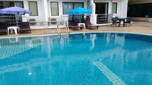 A swimming pool with tiled edges, sun loungers, and umbrellas. - Best Beach Villa (Pattaya)