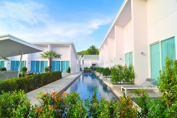 Un hotel moderno con piscina, zona de estar al aire libre y jardín cuidado.