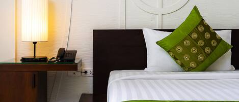 A hotel room with a bed, a nightstand with a lamp, and a telephone.