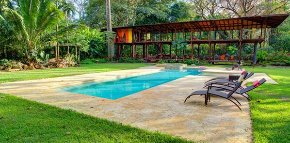 Una piscina al aire libre, sillones reclinables de piscina