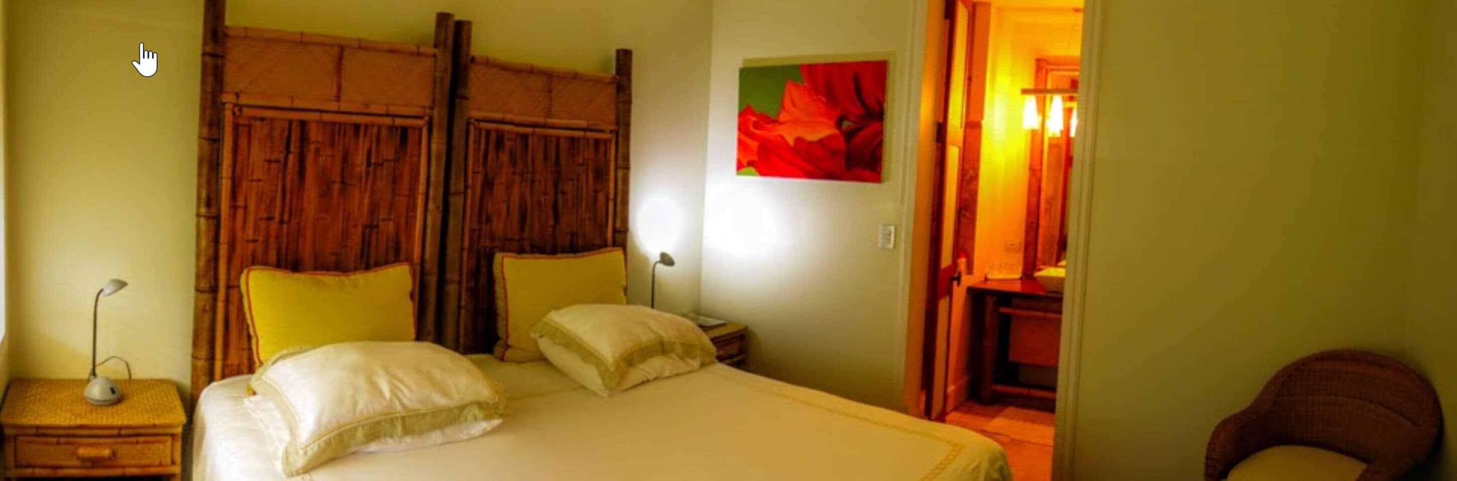 Una habitación con cama, mesitas de noche, una lámpara y un cuadro en la pared.