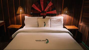 A hotel room with a bed, two nightstands, a decorative fan, and a lamp on each nightstand.