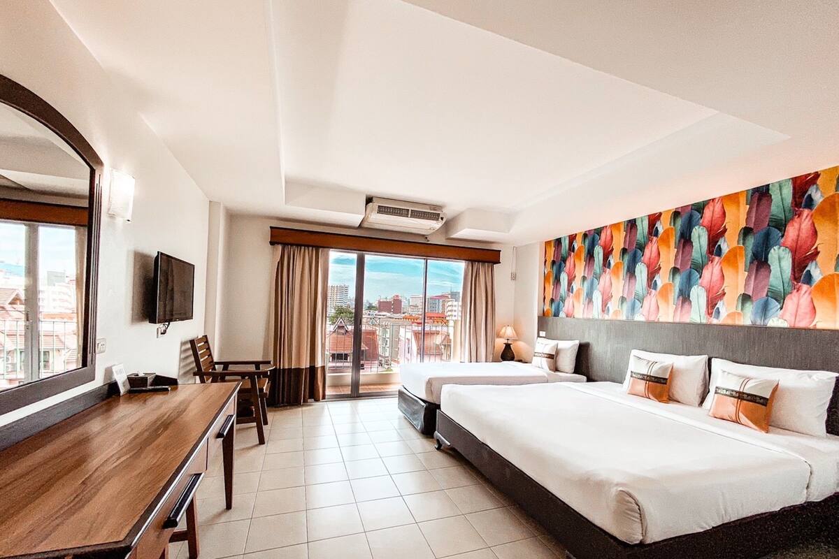 Une chambre d’hôtel avec un grand lit, un bureau et une vue sur la ville par la fenêtre.