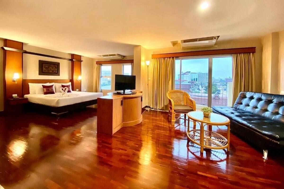 Une chambre d’hôtel avec un lit, un canapé, une télévision, un bureau et une vue sur la ville.