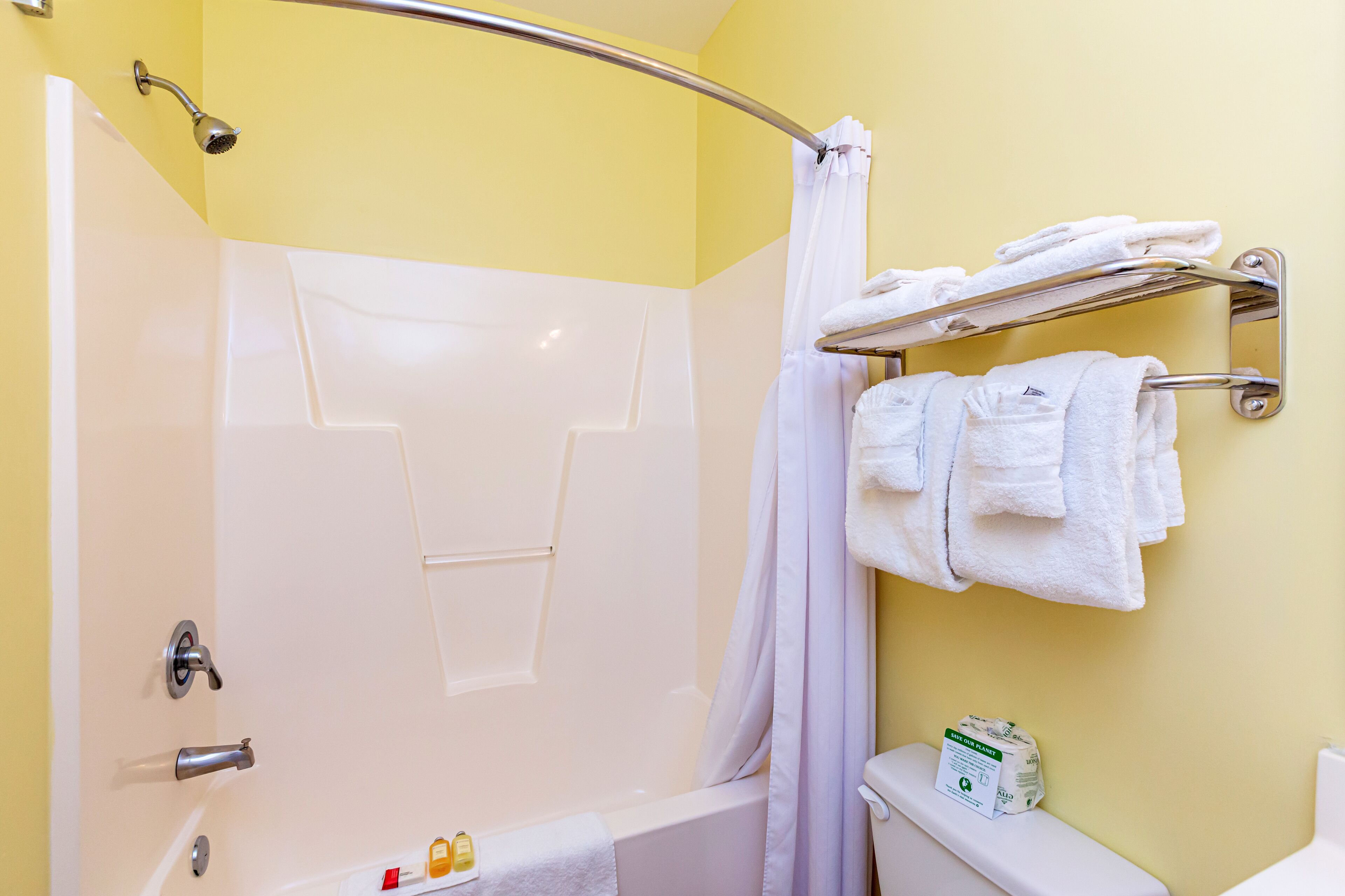 A bathroom with a shower, a toilet, and a towel rack with towels.