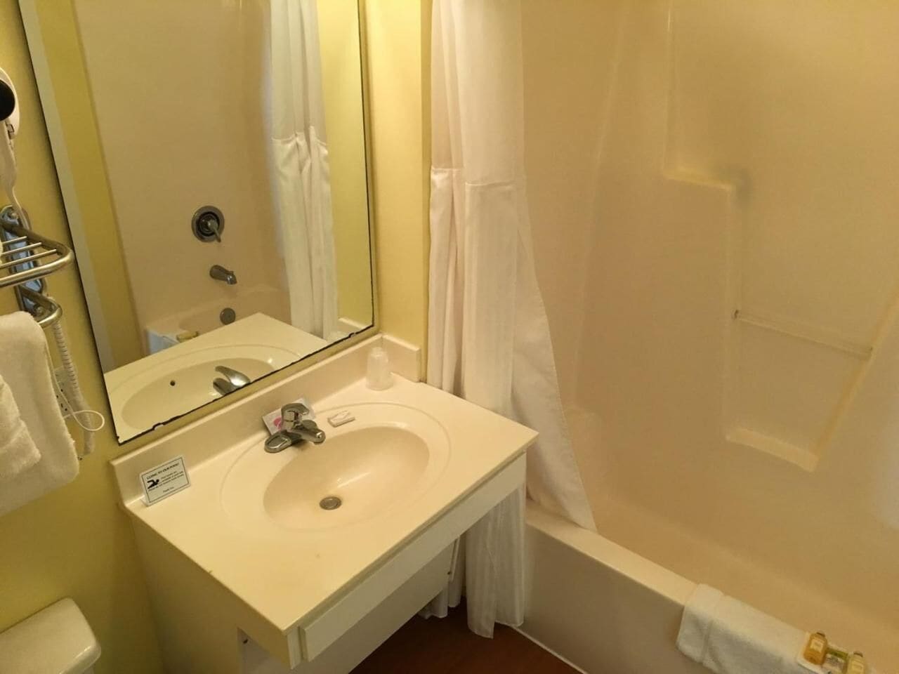 Un baño con lavamanos blanco, espejo y bañera.