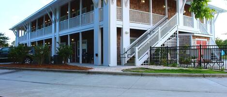 A two-story building with a covered front porch and a staircase leading to the upper level.