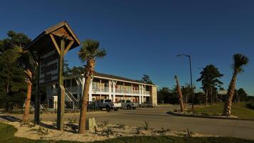 A motel with a two-story structure, a covered parking area, and palm trees in the vicinity.
