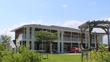 A multi-story building with balconies, a playground, and a red car parked in front.