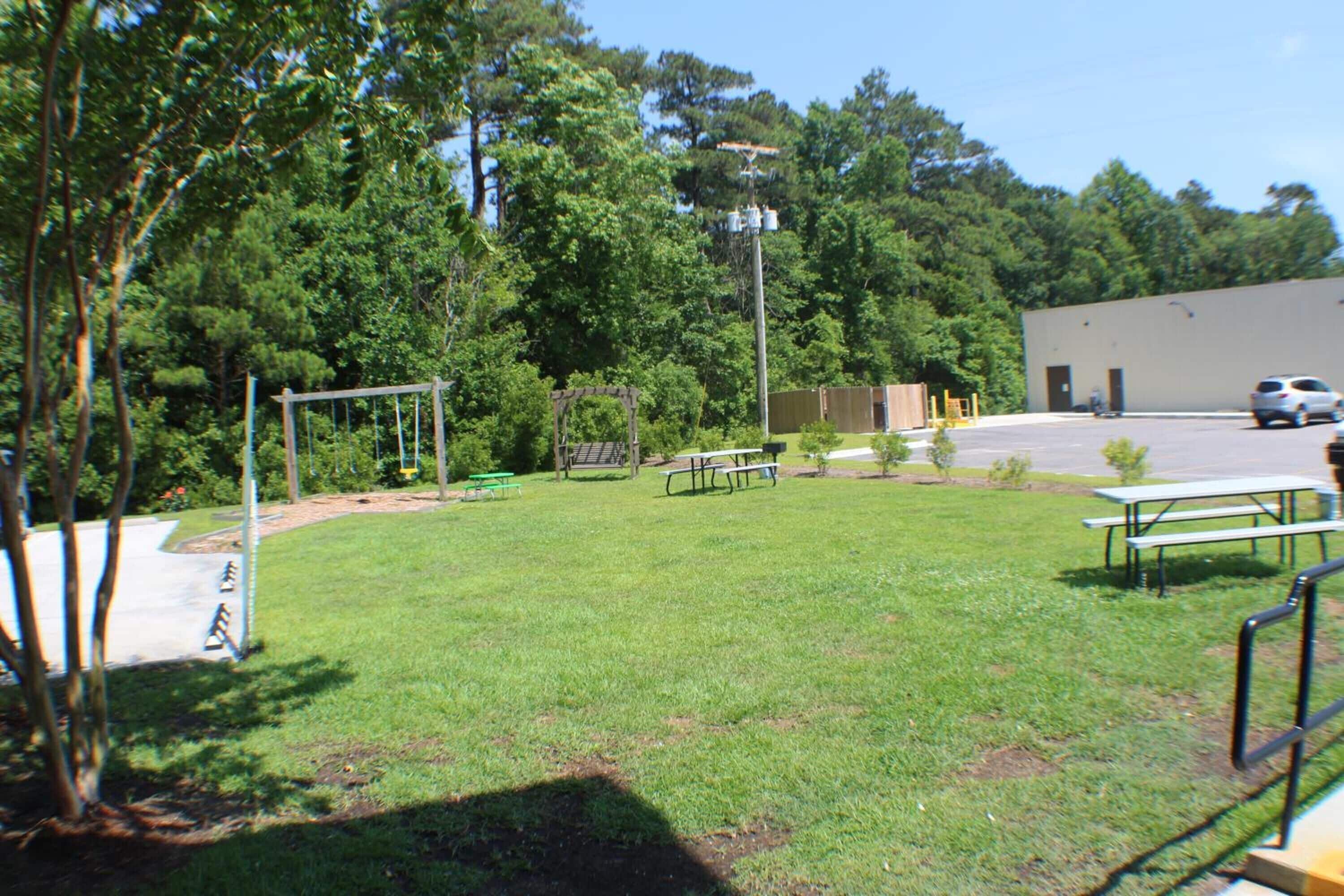 A grassy area with picnic tables and a playground.