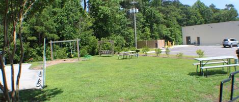 A grassy area with picnic tables and a playground.