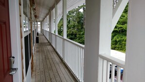 A covered wooden deck with white railings, leading to a door. - Topsail Shores Inn (Sneads Ferry)